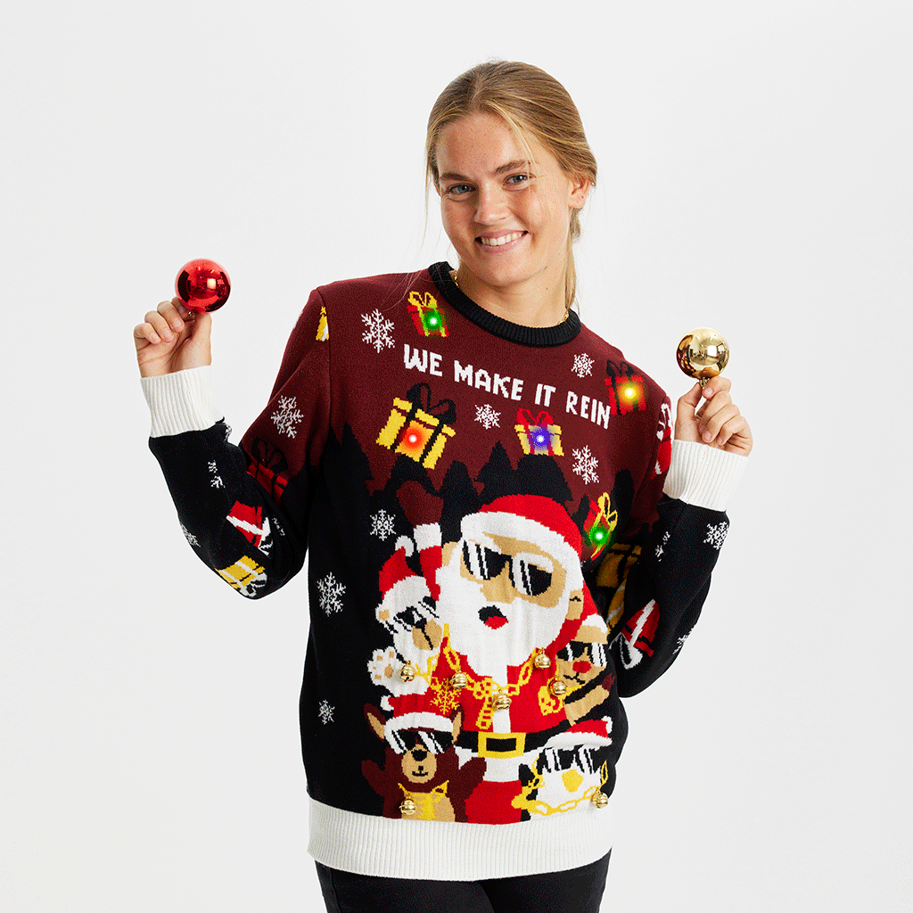 Une femme souriante portant un pull de Noël rouge et noir avec le Père Noël et des lumières.